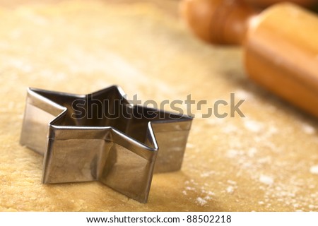 Star-shaped cookie cutter and rolling pin on dough (Selective Focus, Focus on the two front edges of the star-shaped cutter)