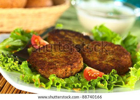 Vegetarian lentil burger made of brown lentils and grated carrots served on lettuce (Selective Focus, Focus on the front of first burger on the left)
