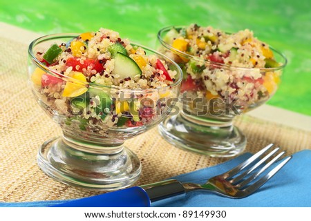 Delicious vegetarian quinoa salad in glass bowls with bell pepper, cucumber and tomatoes (Selective Focus, Focus on the salad in the front of the left bowl)