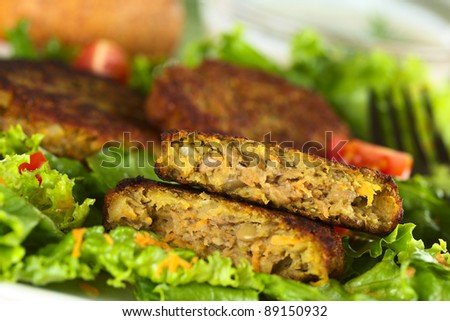 Vegetarian lentil burger made of brown lentils and grated carrots served on lettuce (Selective Focus, Focus on the upper half burger)