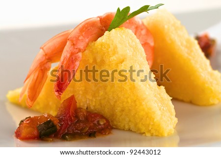 Polenta slices with cooked shrimp and Colombian hogao sauce (Selective Focus, Focus on the the tail of the first shrimp and part of the sauce below)