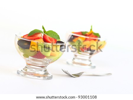 Fresh fruit salad with strawberry, kiwi, mango and grapes in glass bowl garnished with mint leaf (Selective Focus, Focus on the mint leaf in the first bowl)