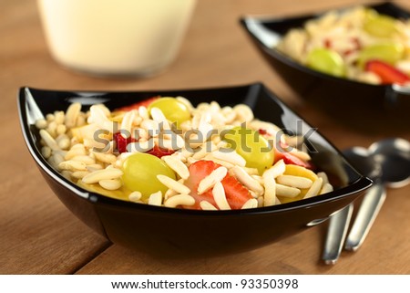 Puffed rice cereal with fresh strawberries, bananas and grapes (Selective Focus, Focus on the strawberry and the grape in the front)
