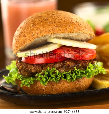 Vegetarian lentil burger in wholewheat bun with lettuce, tomato and cucumber (Selective Focus, Focus on the front of the sandwich)