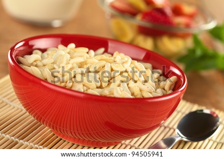 Puffed rice cereal with fruits and milk in the back (Selective Focus, Focus in the middle of the bowl)