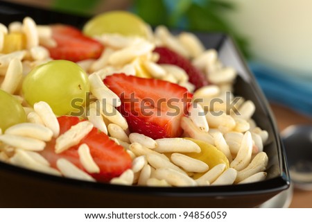 Puffed rice cereal with fresh strawberries, bananas and grapes (Selective Focus, Focus on the front edge of the strawberry in the middle of the image)