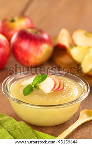 Fresh homemade apple sauce with apples in the back (Selective Focus, Focus on the front of the apple slices on the sauce)