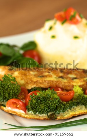 Broccoli and tomato omelette with mashed potato and watercress salad (Selective Focus, Focus on the broccoli floret in the front)