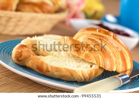 Two half croissants with strawberry jam in the back (Selective Focus, Focus on the front of the upper croissant half)
