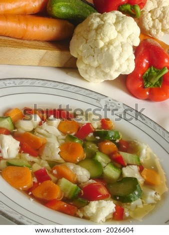 Vegetable â€œminestroneâ€� soup with fresh veggies in the background
