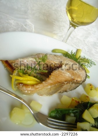 Delicious salmon steak dinner served with olive oil dressing and accompanied with cooked potato and spinach.