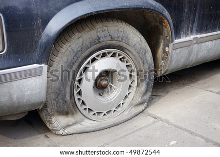 Car parked on a roadway with a flat tire