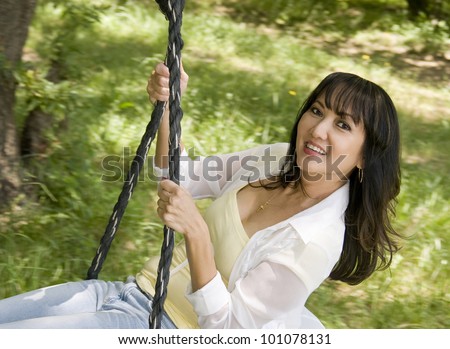 Beautiful asian woman swinging, sitting on a rope swing, springtime