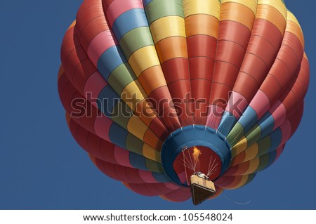Looking up at beautiful balloon with the burner on, flames are visible, nice blue sky, triangular basket