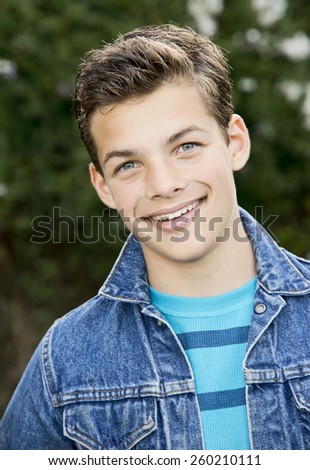 Smiling teenage boy outside, wearing denim jacket, vertical format, 13 yrs old