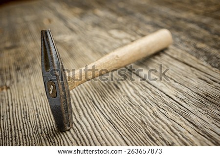 Old hammer with pointed end resting on weathered wooden boards, lots of texture