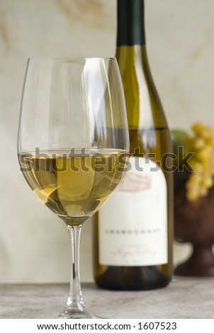 glass of chardonnay,bottle and grapes in background,label is soft focus
