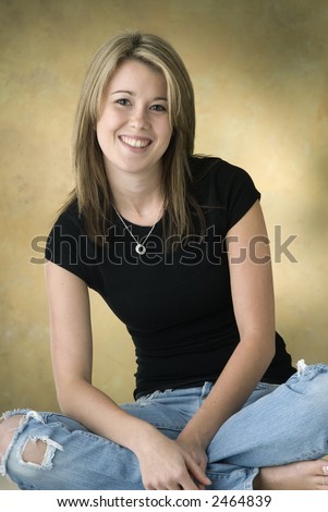 smiling young woman,blond hair,casual dress black top and worn out jeans,small necklace