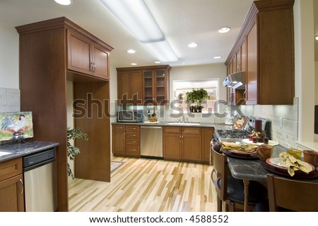modern kitchen with wood floor,wood cabinets,stainless appliances,microwave,recessed lighting,marble counters