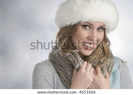 pretty blonde woman wearing fur hat covered with snow flakes,winter feeling