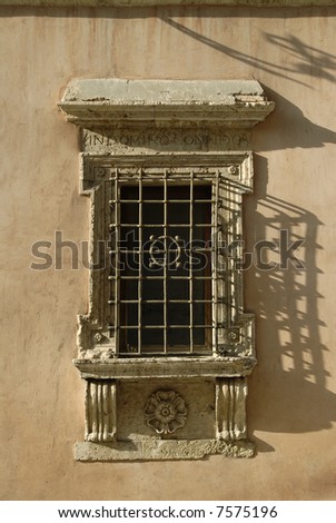 ornate window in Assisi, Italy, with an incription, translation In God we Trust,
