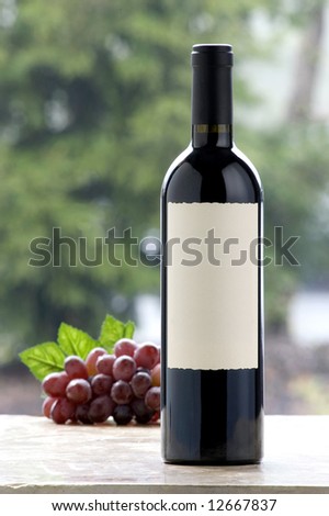wine bottle with blank label, grapes in background,outdoors