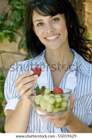 happy pretty brunette having a bowl of fruit outside on her home patio