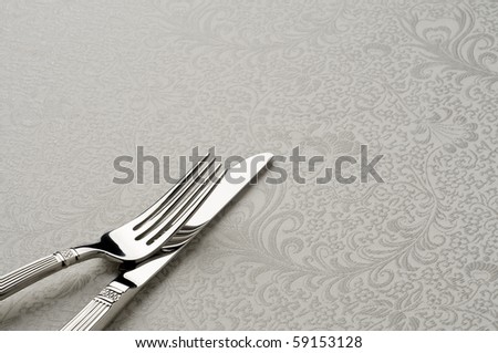 knife and fork on ornate table cloth, room for copy