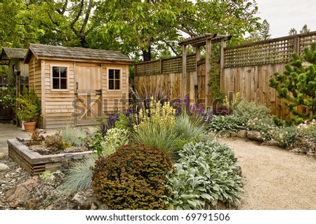 beautifully landscaped backyard with small wooden shed, fence and pathway
