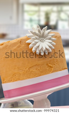 Decorative cake with kitchen background, orange frosting with large edible flower