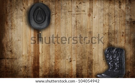 Black Cowboy boots and hat against a weathered cedar background panel.