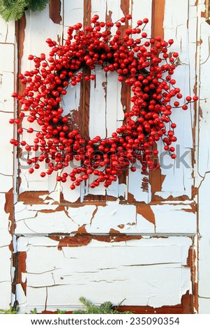 Christmas wreath of red holly berries against a vintage wooden door.