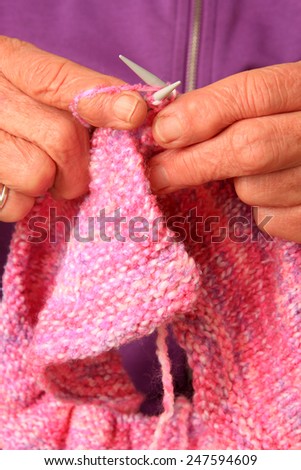 Close up of a senior lady\'s hands knitting a pink baby blanket. Also available in horizontal.