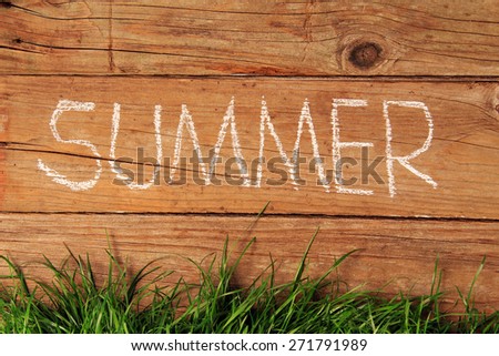 Summer written in chalk on a wooden fence.