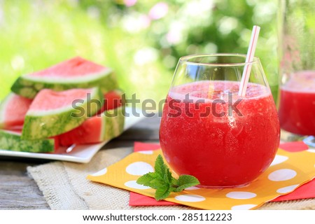 Watermelon drinks outside in the garden with straws and fresh mint. Also available in vertical.