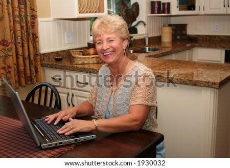 Grand-ma in the kitchen using her laptop.