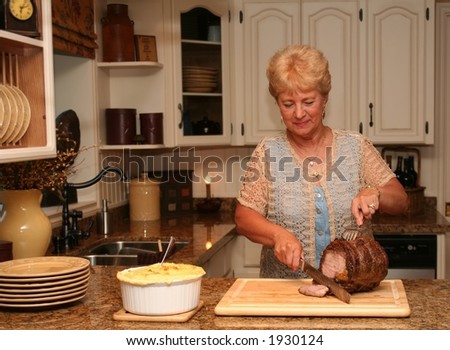 Grand-ma in a country kitchen carving a beef roast.