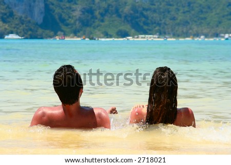 Young couple relaxed side by side in the water on a beach.