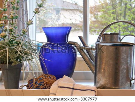 Watering can, flowers and a vase on a tray in the kitchen of a show home.