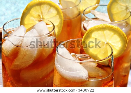 Four glasses of lemon ice tea, outside by the pool.