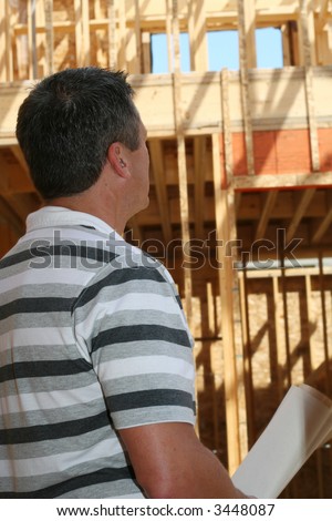 Man holding the blue prints of his new home still under construction.