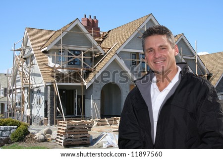Friendly builder in front of home under construction.