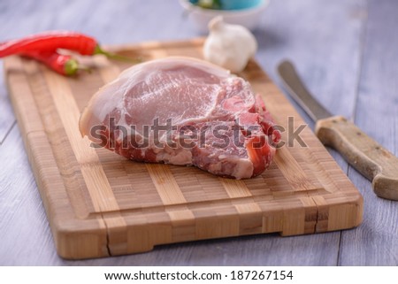 Raw pork chops on the cutting board with some chili and garlic