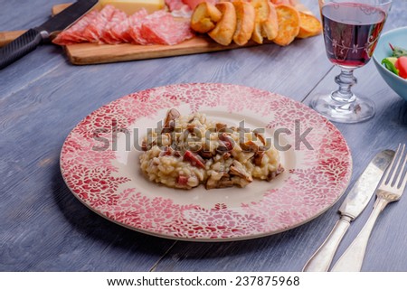 Risotto on a wood table with some antipasto in the background