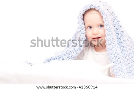 Little cute boy under blanket sitting on the bed (after taking bath)