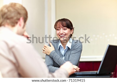 Boss talking to his employee and she is smiling