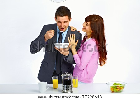 Businessman has breakfast before go to work and his wife standing near him and hugging him