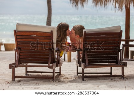 husband and wife relaxing on sunbeds on the beach.