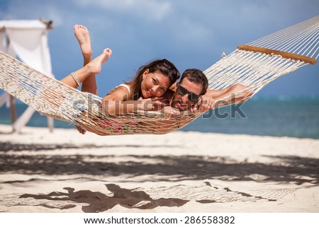 young loving couple on their wedding day, relaxing in beach hammock, outdoor beach wedding in tropics