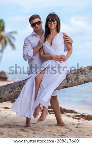 Young loving couple. Girl sitting on the palm tree.
